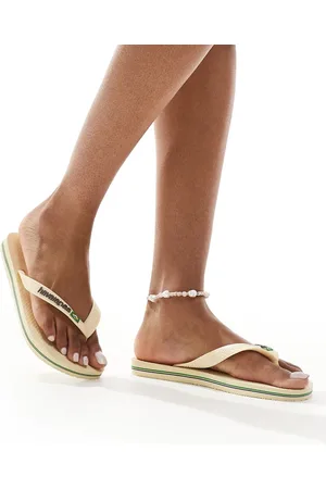 Havaianas – Zehenstegsandalen in Buttercremeweiß mit brasilianischem Logo